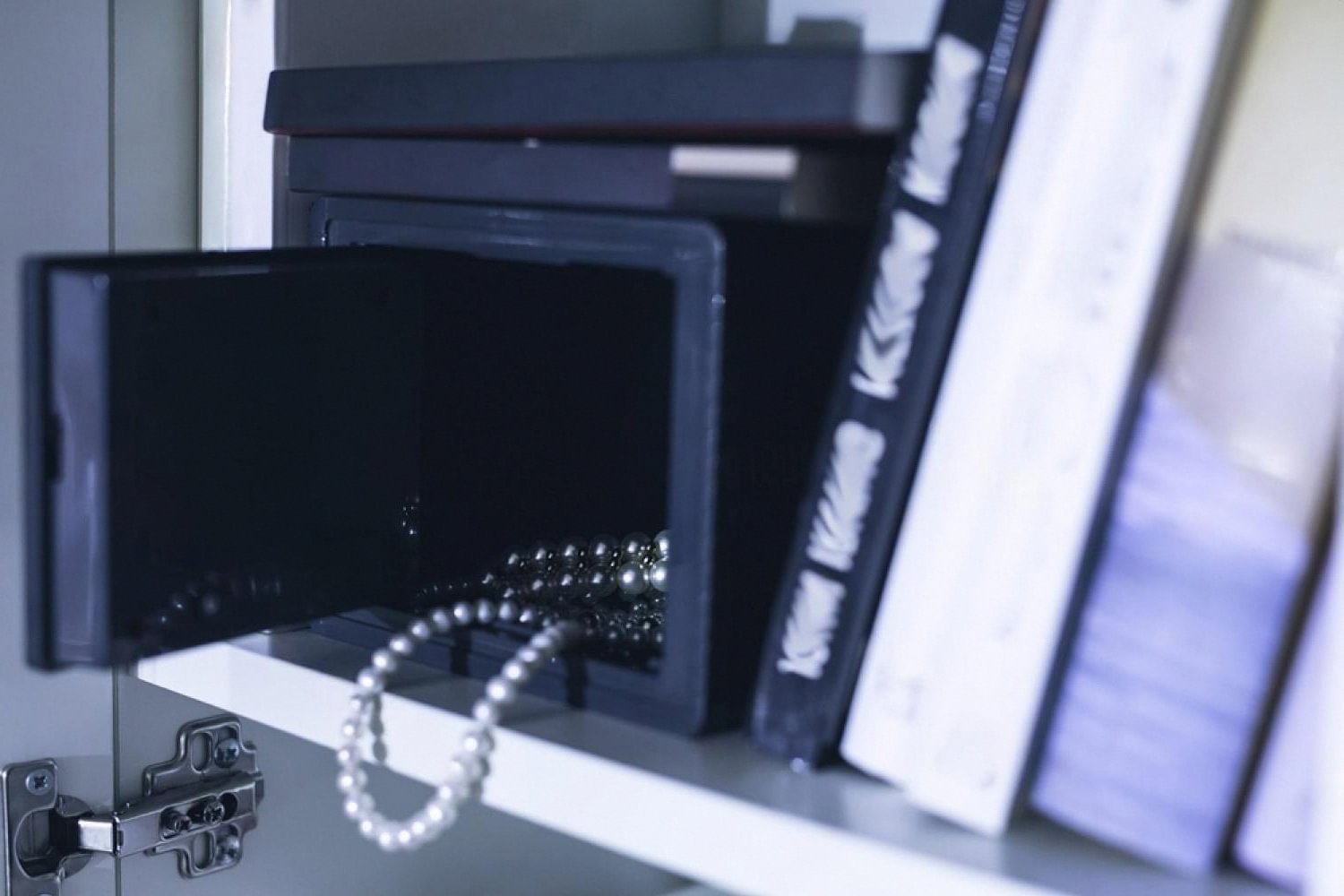 Small home jewelry safe with a pearl necklace inside, hidden behind a cabinet